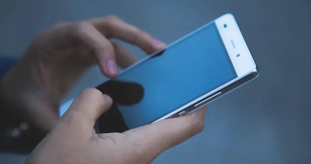 Mãos digitando em um celular com a tela de mensagens