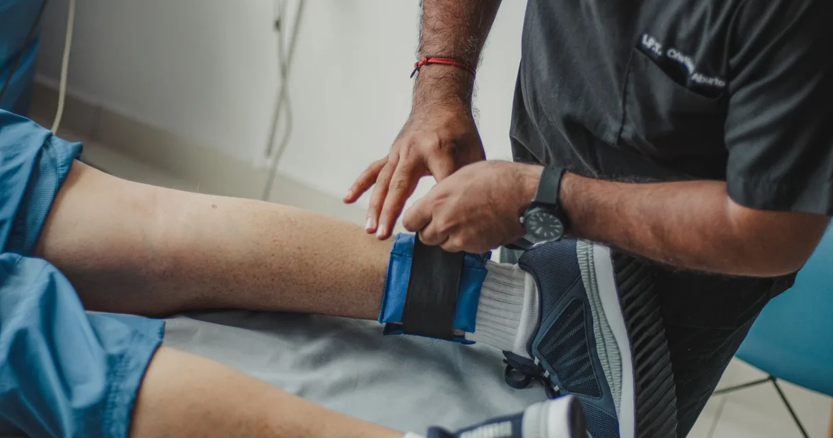Fisioterapeuta ajustando uma faixa de treino na perna de um paciente