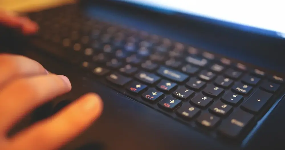 Mão sobre o teclado de um notebook, cena de quem escolhe plataformas de fontes de letras para a bio